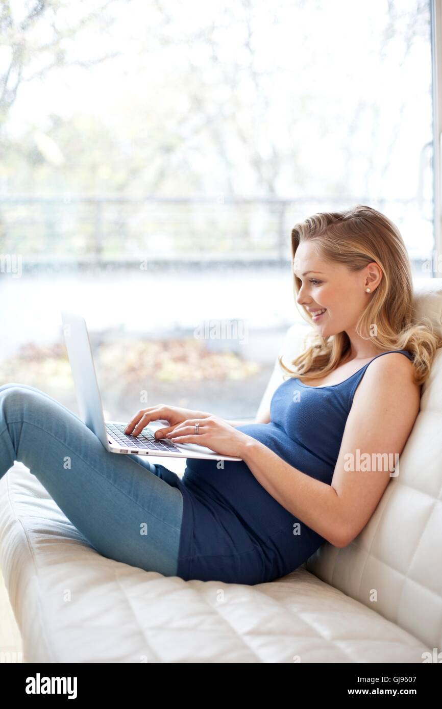 Modello rilasciato. Donna incinta utilizzando laptop. Foto Stock