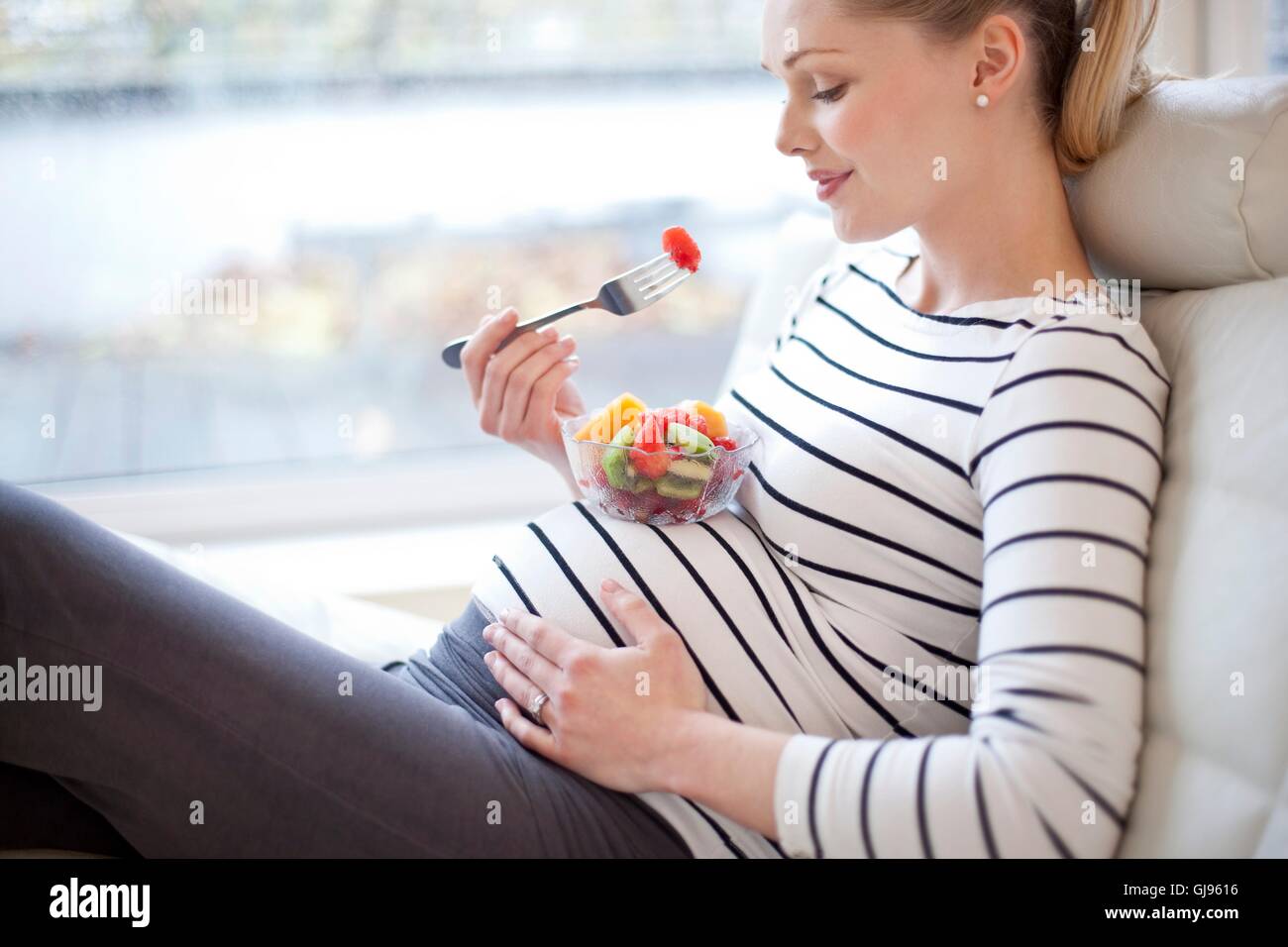 Modello rilasciato. Donna incinta di mangiare insalata di frutta. Foto Stock