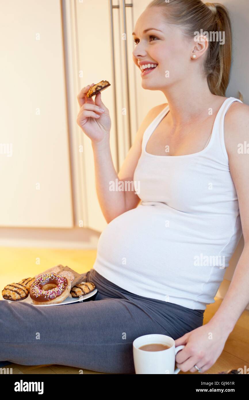 Modello rilasciato. Donna incinta di mangiare i biscotti. Foto Stock