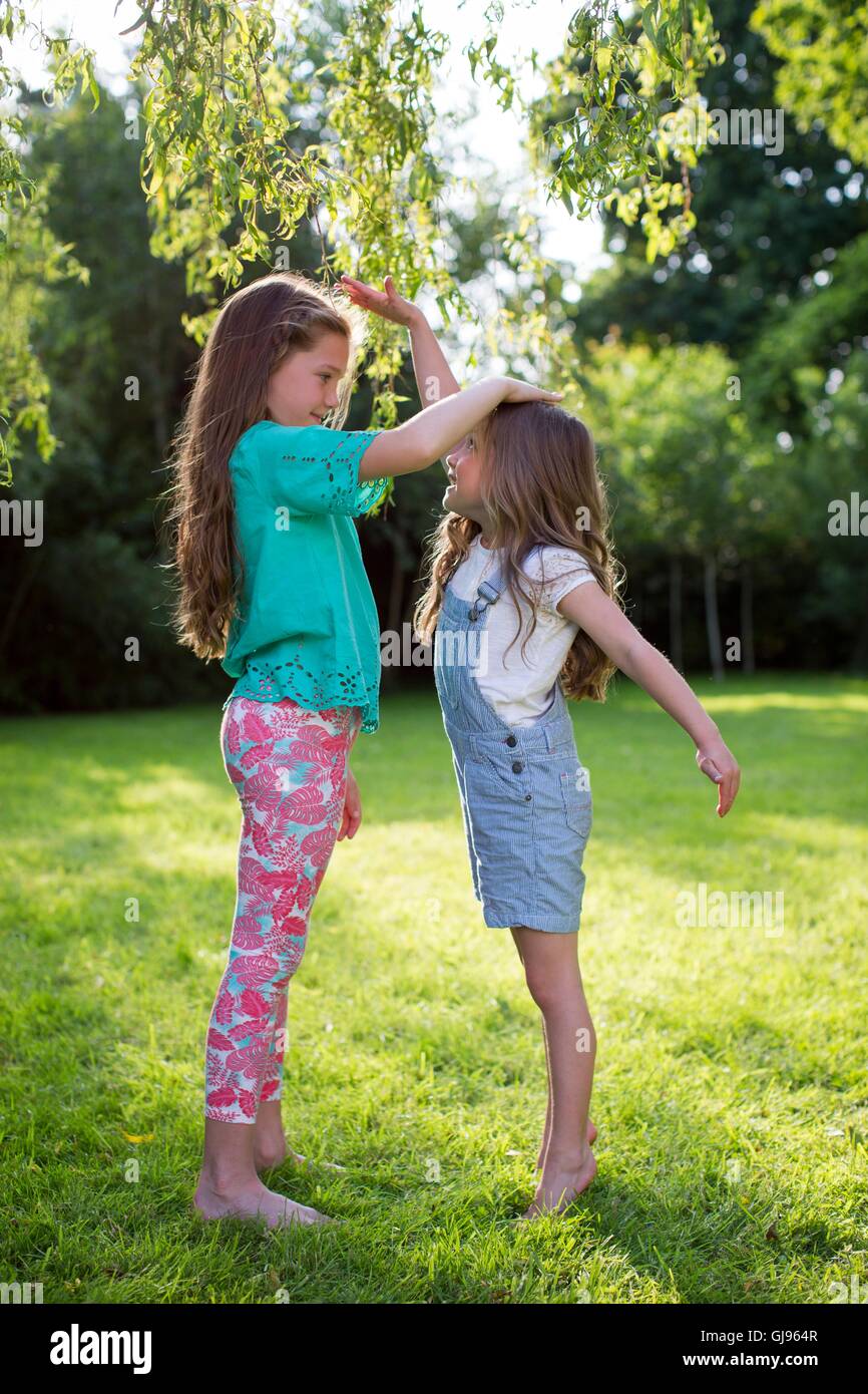 Proprietà rilasciato. Modello rilasciato. Due sorelle misurando la loro altezza l'uno contro l'altro. Foto Stock