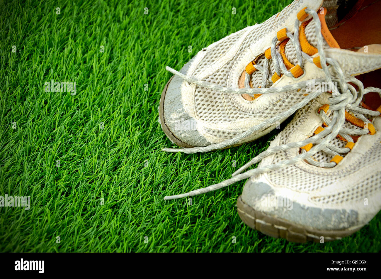Vecchio sneakers sul campo in erba sintetica. Foto Stock