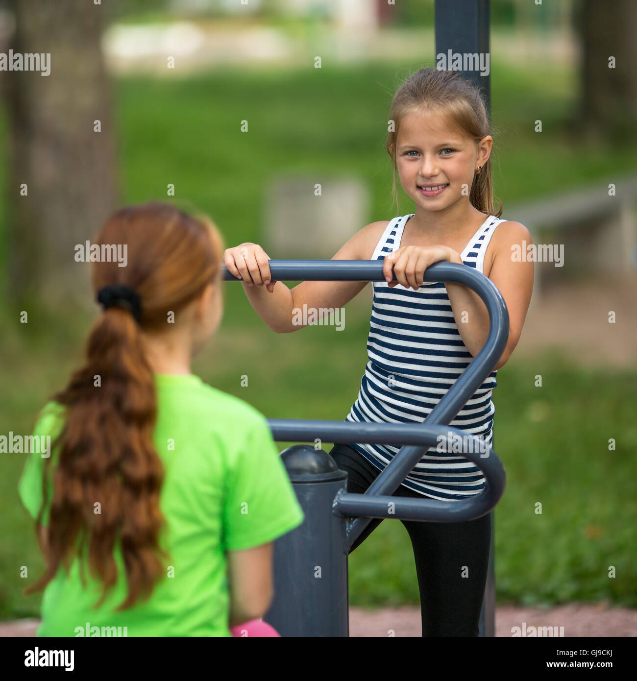 I ragazzi delle ragazze di fare ginnastica sul pubblico di attrezzature sportive all'aperto. Foto Stock