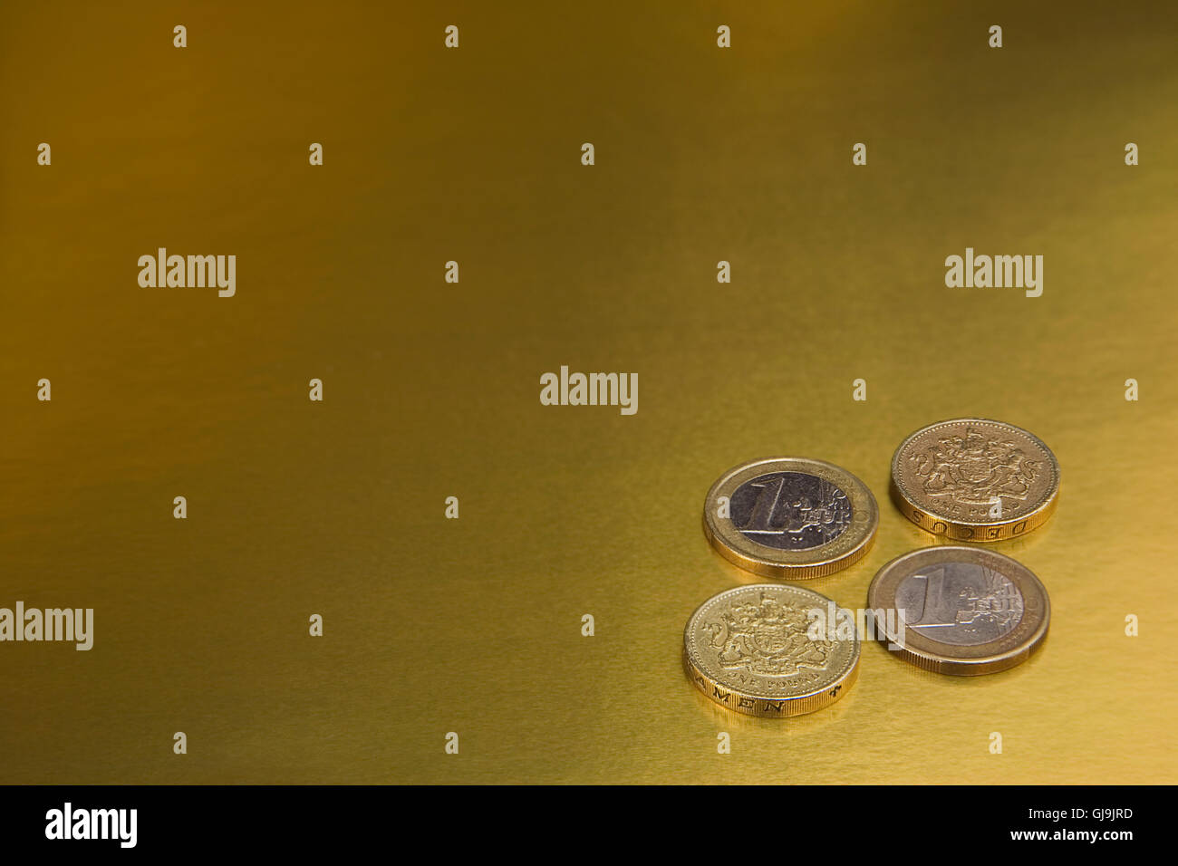 British una libbra e una delle monete in euro su un fondo dorato Foto Stock