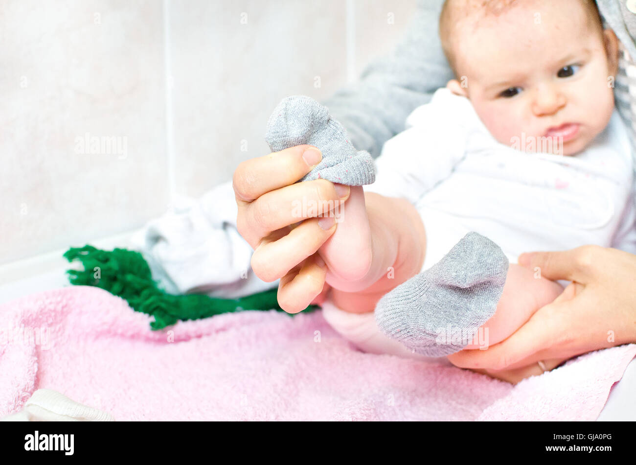 Mettere calze grigio al neonato Bambino Foto Stock