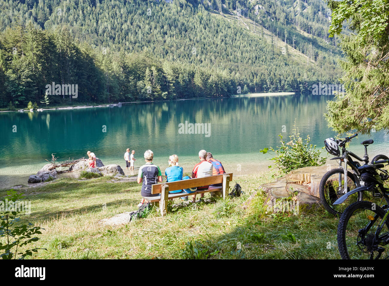 Un gruppo di appassionati di mountain bike di prendere un periodo di riposo su una panchina al bellissimo lago Vorderer Langbathsee in Austria, Salzkammergut Foto Stock