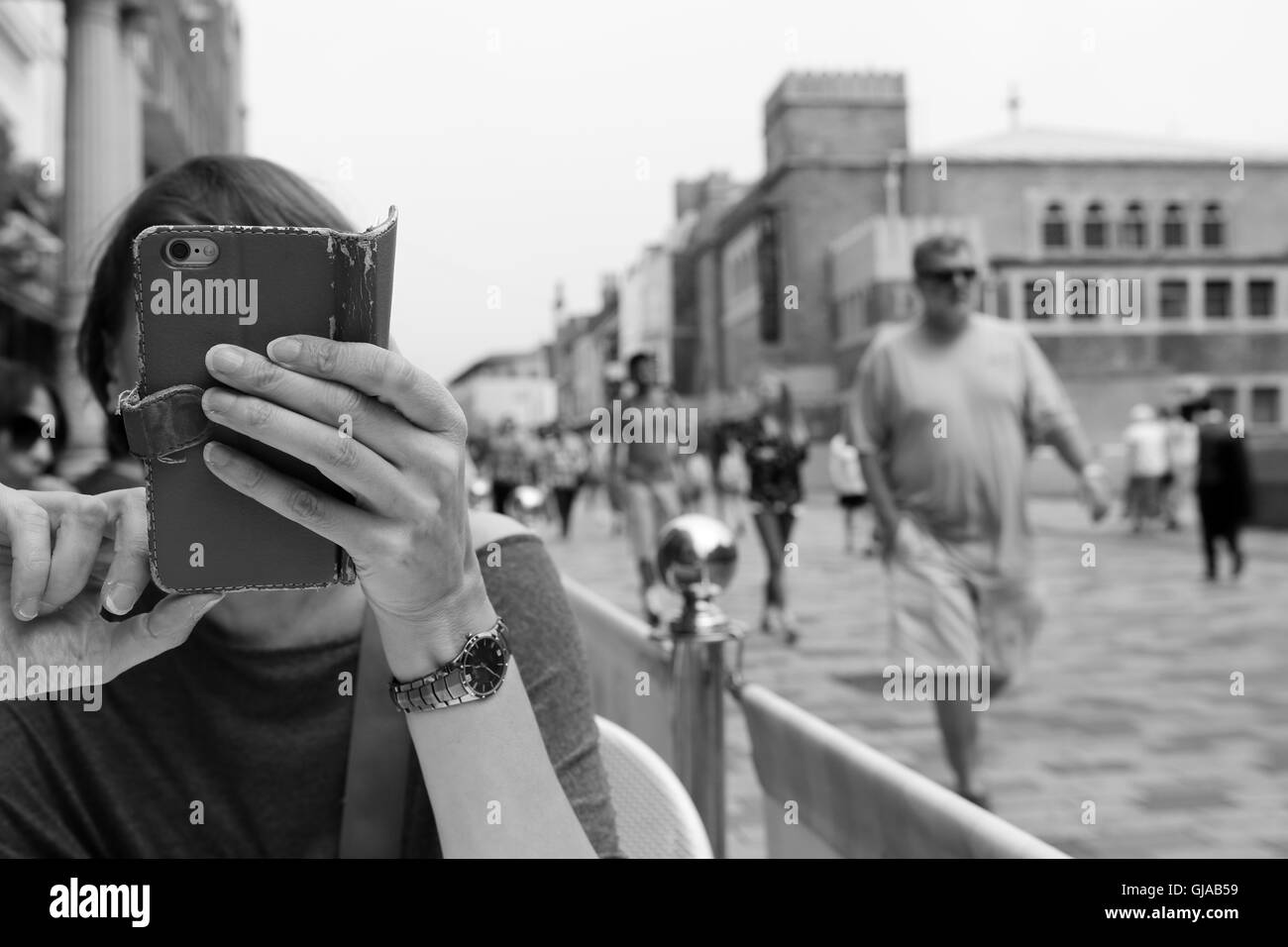 Signora su telefono cellulare oscurando la vista del suo viso così persona davanti non riesco a vedere la sua. Foto Stock