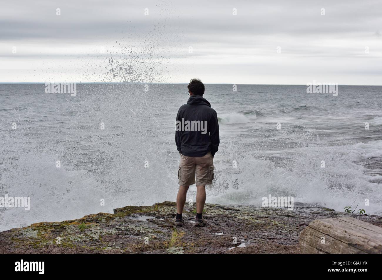 Un giovane uomo visto da dietro, si affacciano su acqua turbolenta al Lago Superior. Foto Stock