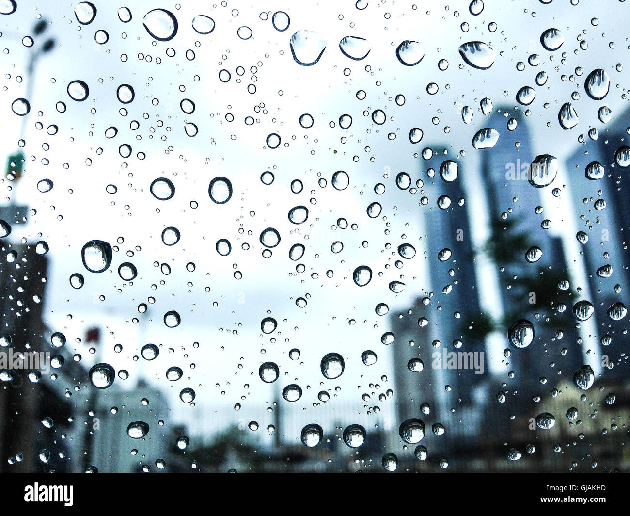 Gocce di pioggia si aggrappano a un finestrino di vetro con skycrapers sullo sfondo Foto Stock