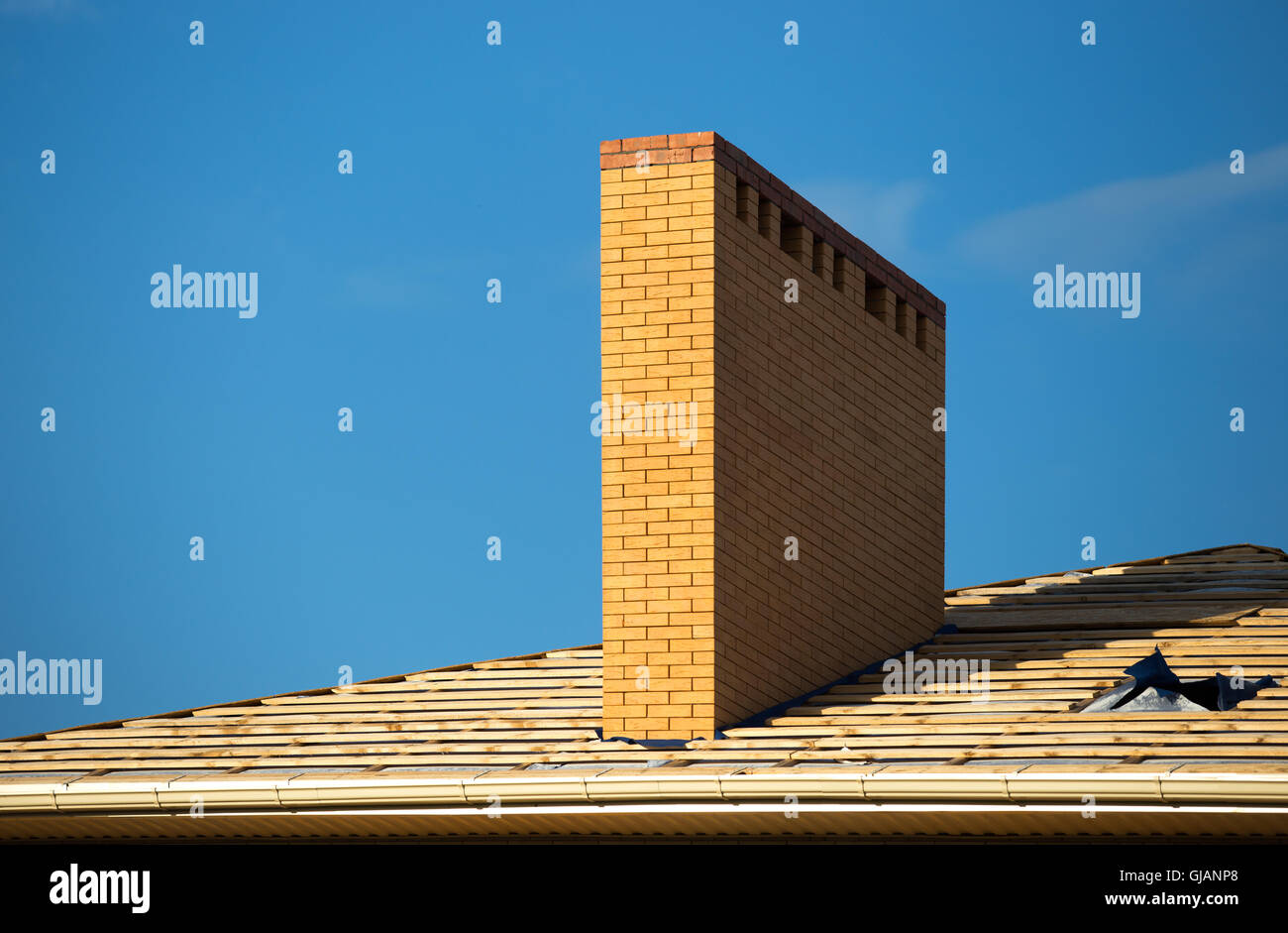 Tetto sotto costruzioni con un sacco di piastrella e mattone giallo camino Foto Stock