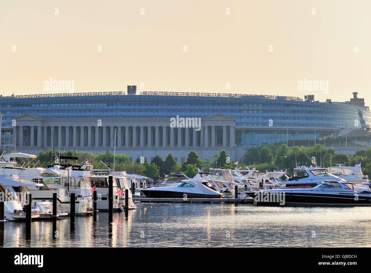 Il sole di setting crea un bagliore nel cielo come salse verso l'orizzonte al di là di Chicago's Soldier Field. Chicago, Illinois, Stati Uniti d'America. Foto Stock