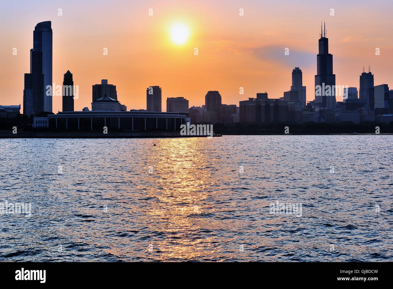 Il sole di setting crea un bagliore colorato nel cielo e in Chicago's Monroe Street Harbour come cali di esso verso l'orizzonte. Chicago, Illinois, Stati Uniti d'America. Foto Stock