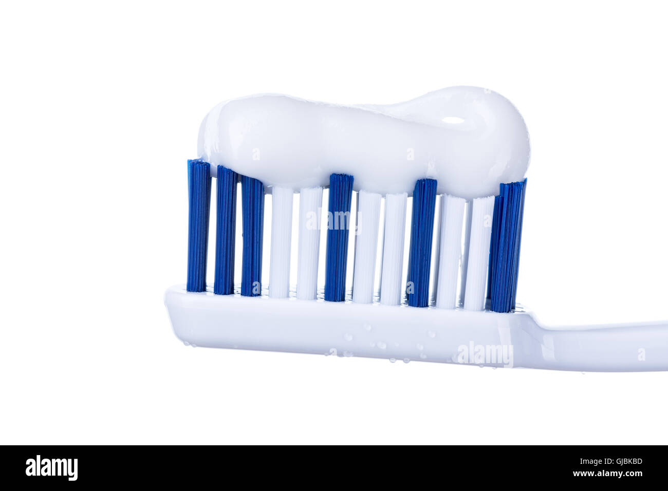 Singola testina di spazzolino da denti con dentifricio e gocce di acqua isolati su sfondo bianco. Foto Stock