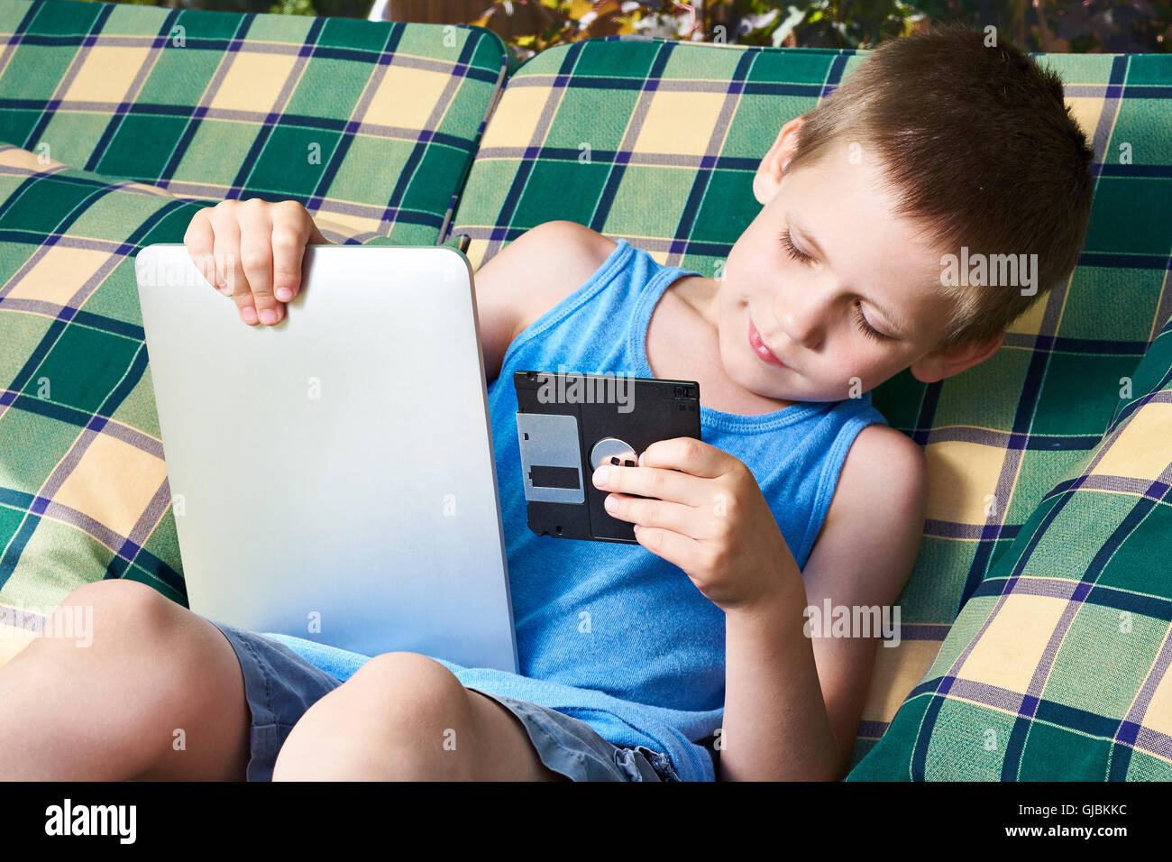 Little Boy con un floppy disk e tablet pc all'aperto Foto Stock
