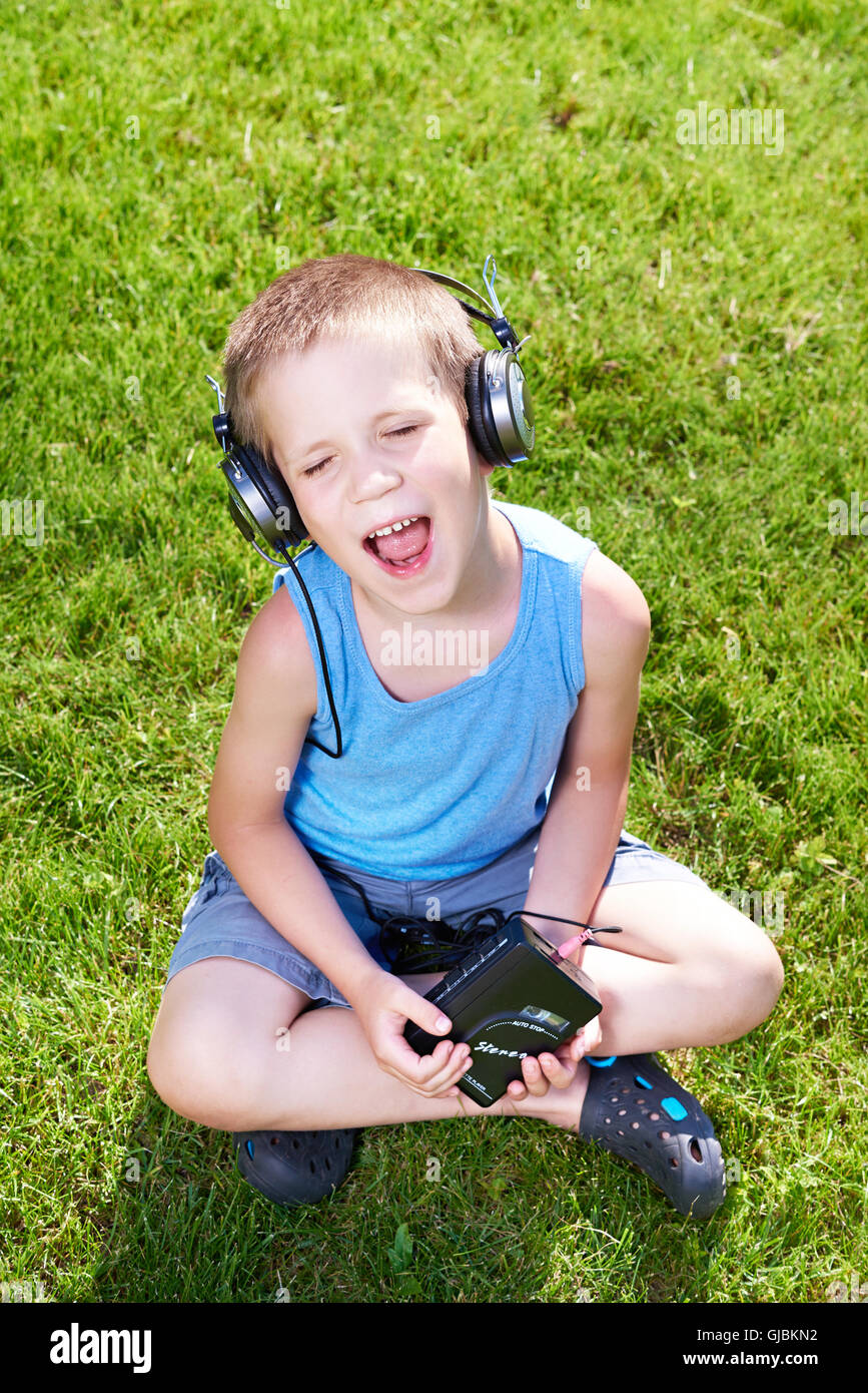 Little Boy con il vecchio lettore di cassette audio e cuffie Foto Stock