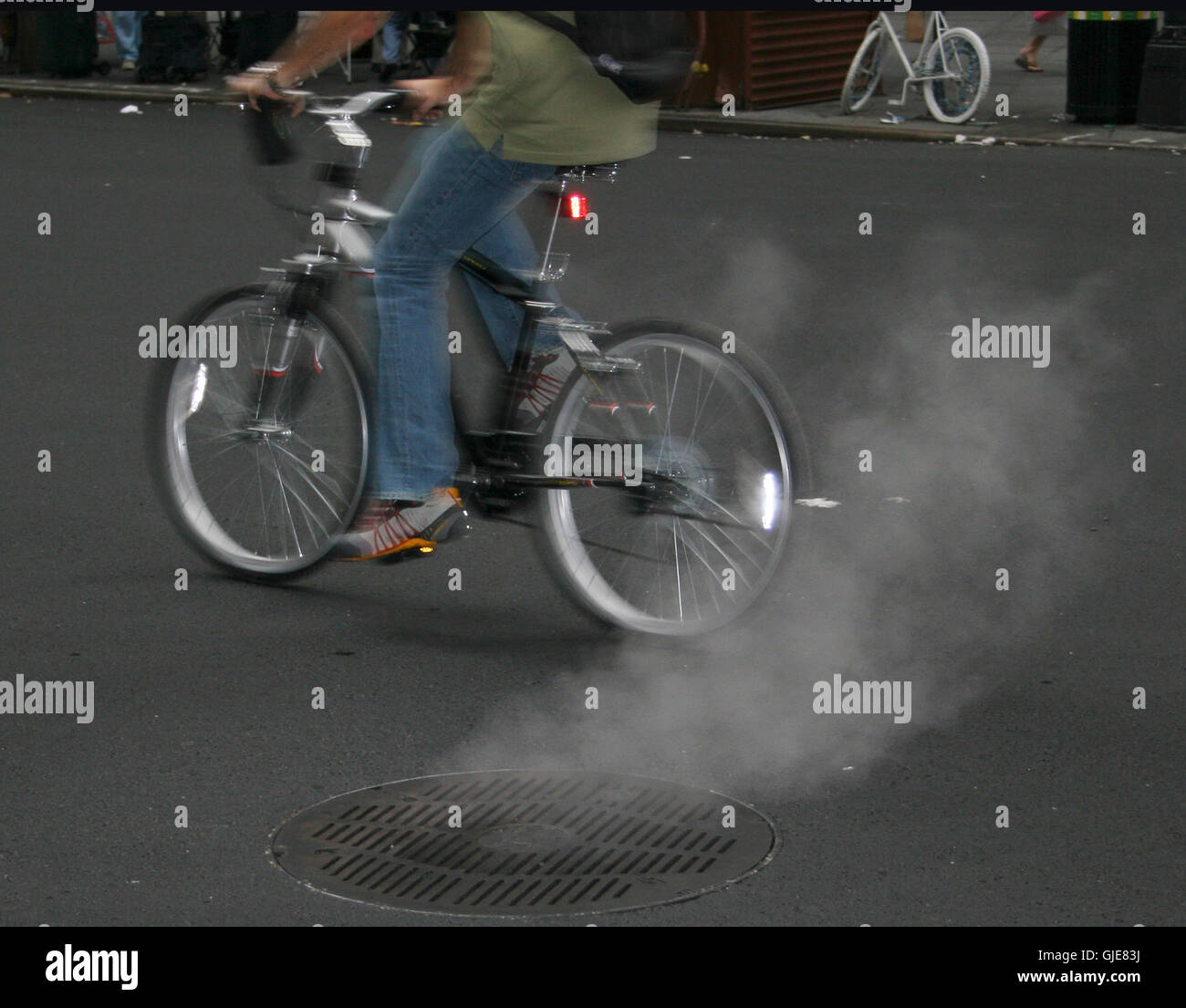 Ciclista su strada con il fumo di una fogna 2008 Foto Stock