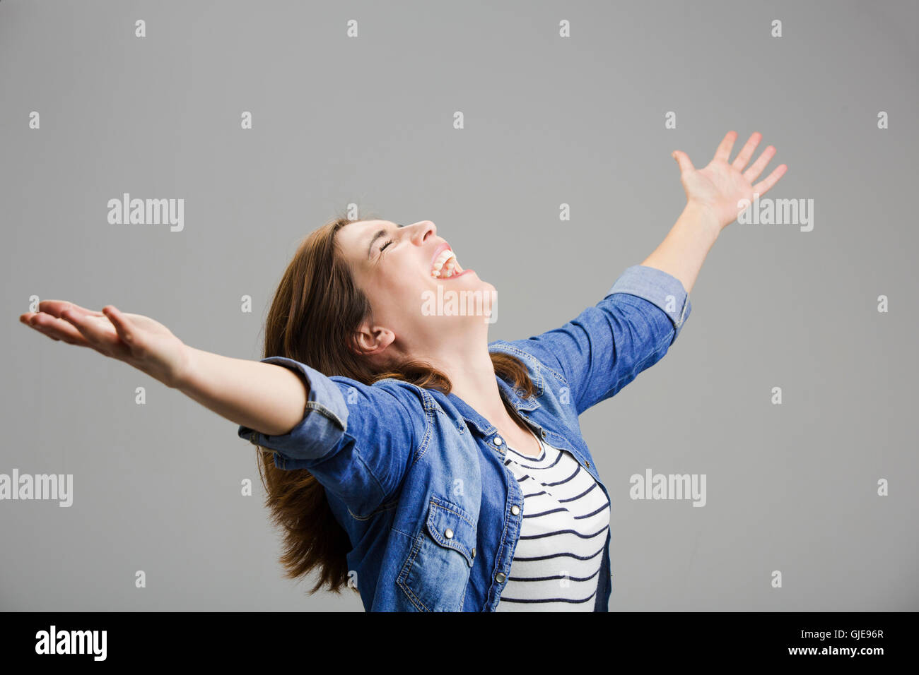 Studio ritratto di una donna felice con le braccia sollevate Foto Stock