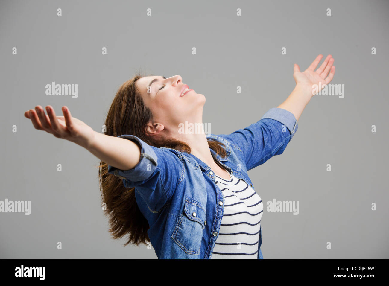 Studio ritratto di una donna felice con le braccia sollevate Foto Stock