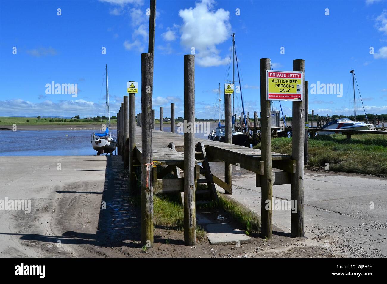 Planked in legno jetty e yacht a vela dal fiume Wyre a Skippool Creek, LANCASHIRE REGNO UNITO Foto Stock