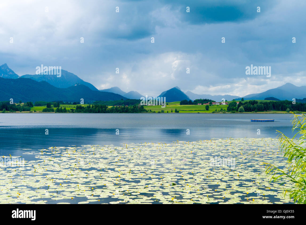 Lago nelle Alpi tedesca con una catena di picchi di montagna all'orizzonte. La riflessione del cielo in acqua Foto Stock