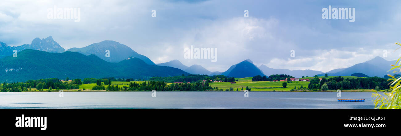 Lago nelle Alpi tedesca con una catena di picchi di montagna all'orizzonte. La riflessione del cielo in acqua Foto Stock