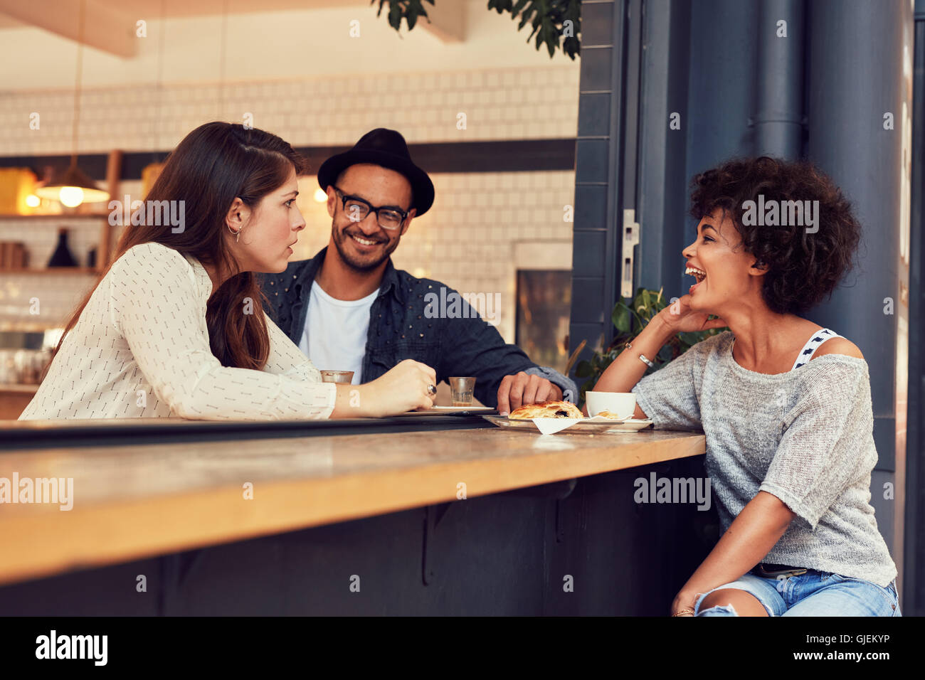 Ritratto di un giovane gruppo di amici a parlare in un bar. Giovane uomo e donna seduta al tavolo del bar e parlare. Foto Stock