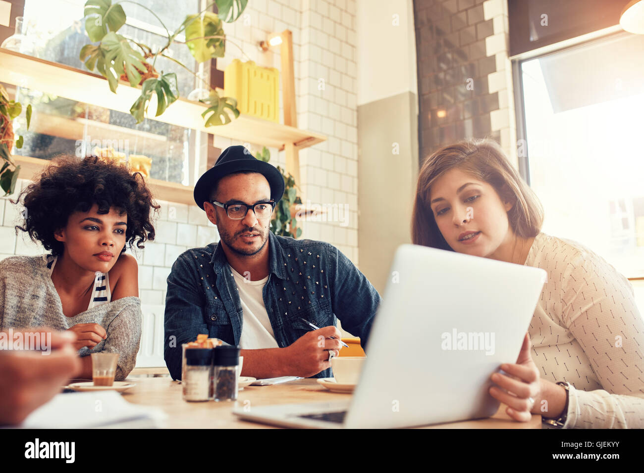 Ritratto di persone creative seduto a un coffee shop e guardando il laptop. Il team Aziende a discutere di nuove idee di progetto in un cafe Foto Stock