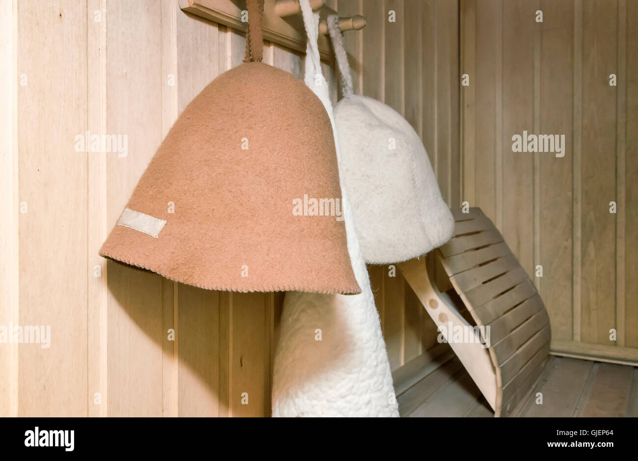 L'interno di una piccola sauna finlandese con pareti in legno. Sulla parete appendere cappelli in feltro per un bagno. Foto Stock