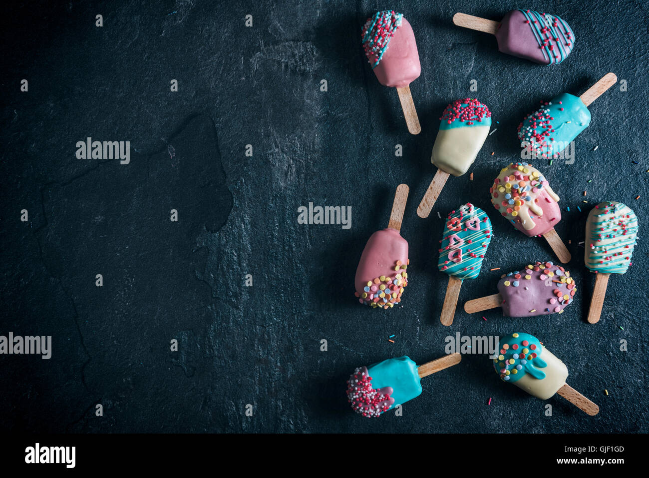 Torta colorata pop nel gelato forma su sfondo scuro con uno spazio vuoto Foto Stock