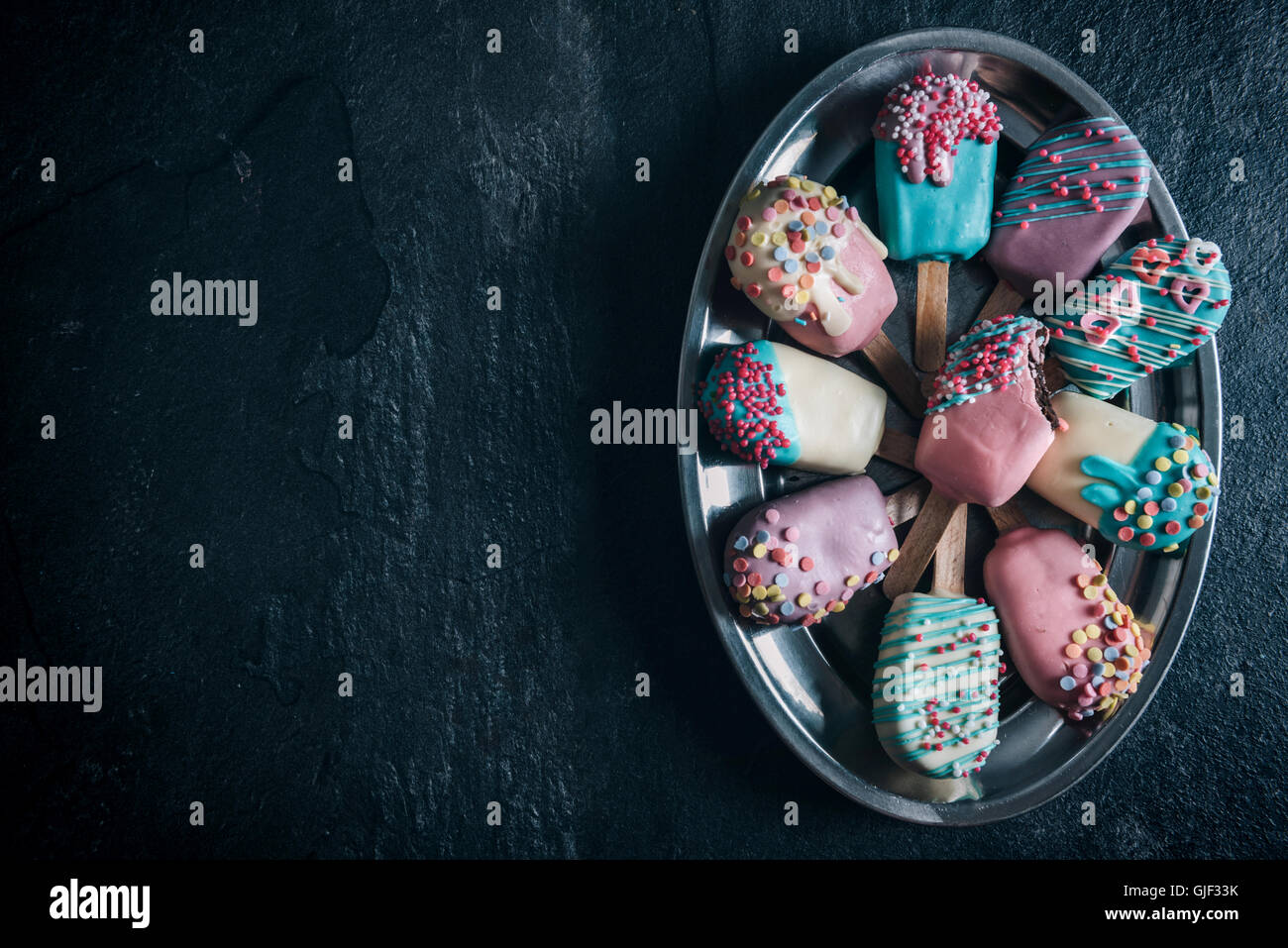 Colorato pop di torta gelato su sfondo scuro con uno spazio vuoto Foto Stock