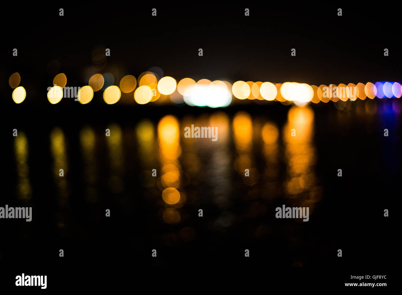 Bella città sfocate luci con effetto bokeh di fondo riflessa sul fondo di acqua Foto Stock