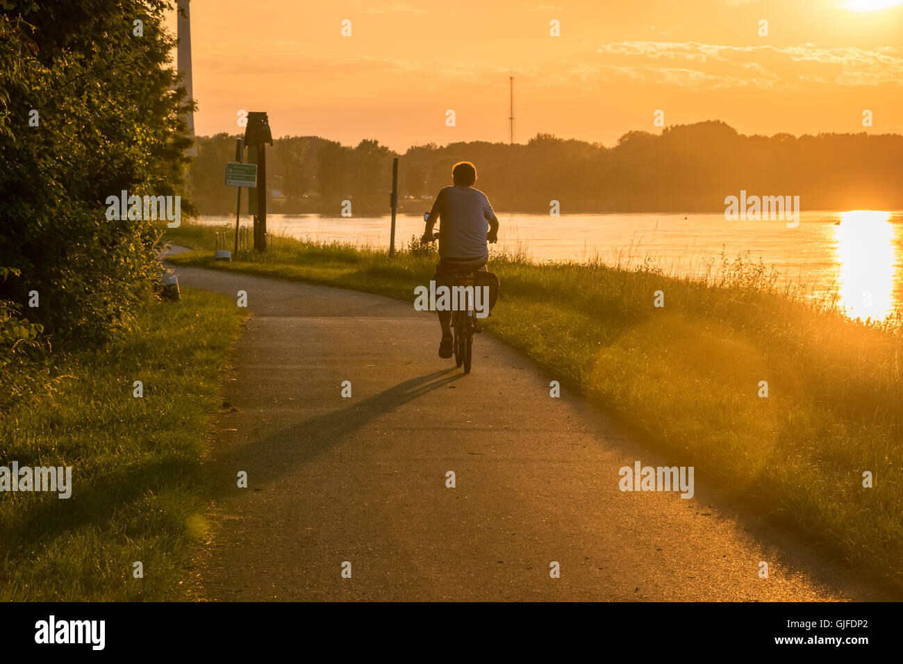 Persona escursioni in bicicletta sul fiume al tramonto umore Foto Stock