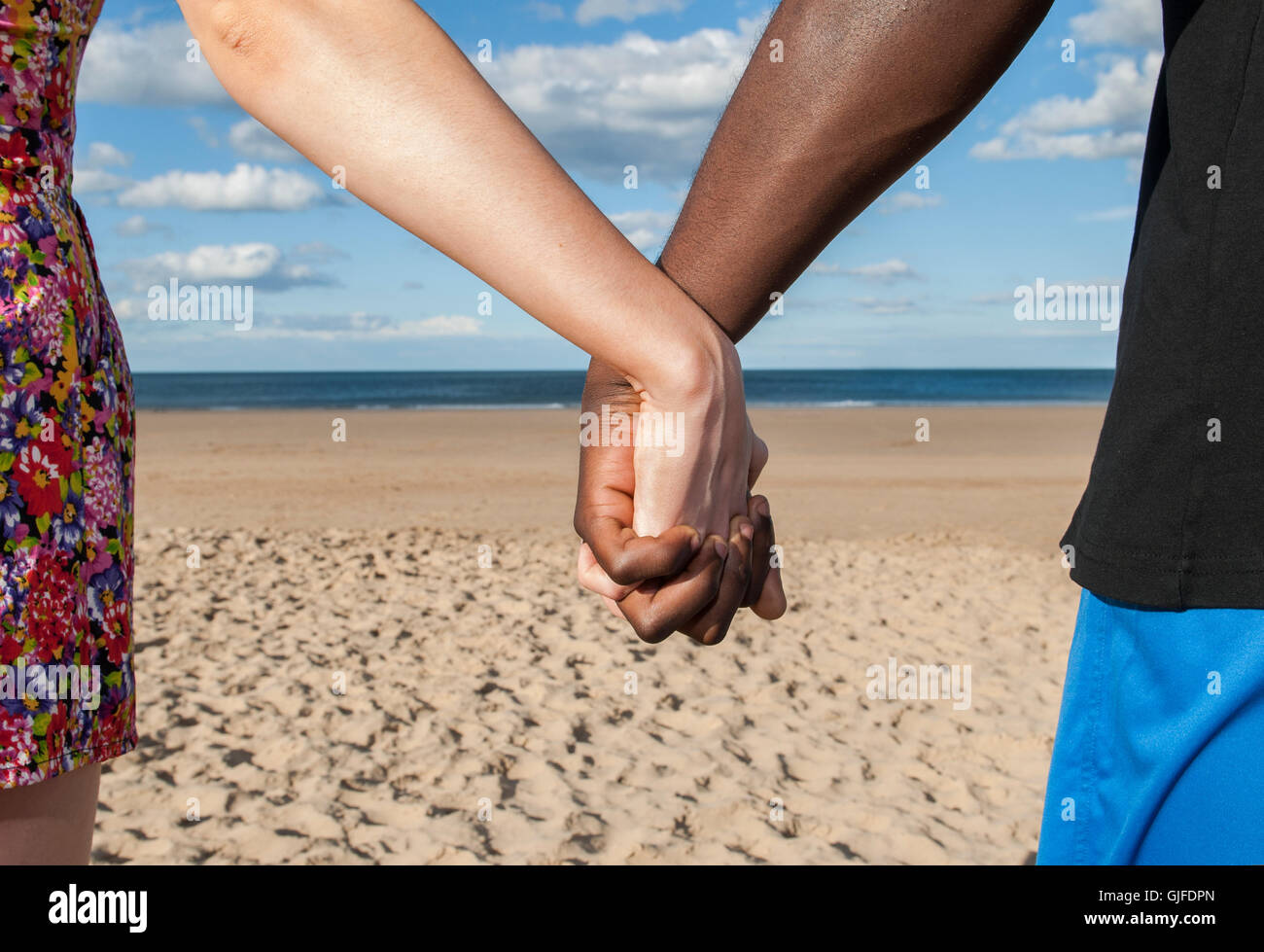 Tenendo le mani la parte del corpo che mostra maschile e femminile multiculturale di razza mista il mare e la sabbia insieme amore il concetto di pace Foto Stock