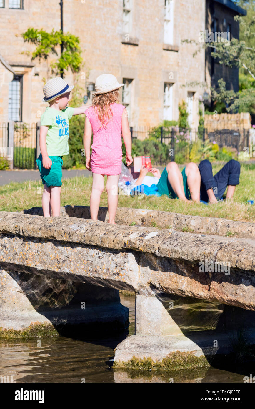 I bambini che giocano nel fiume a Lower Slaughter, Cotswolds, UK. Foto Stock