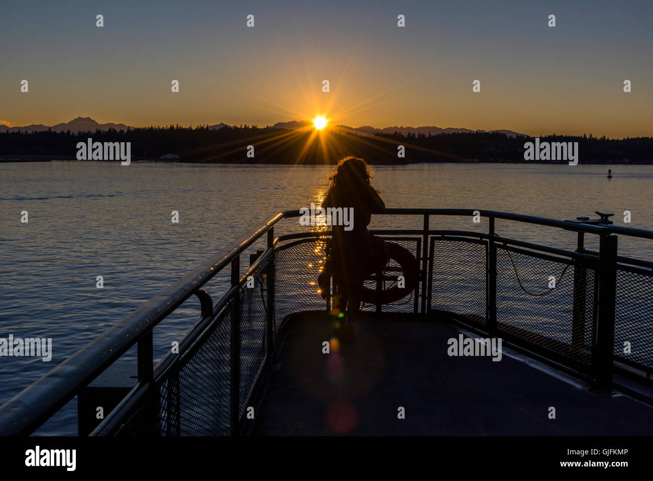 Giovane ragazza a guardare il tramonto sulla Baia di Elliott dal traghetto, Seattle, Washington, Stati Uniti d'America Foto Stock
