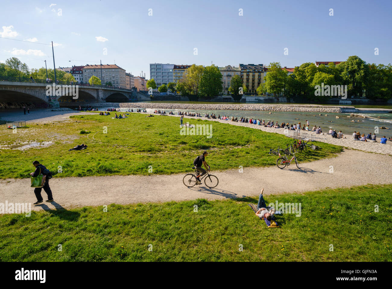 Occupato della primavera o estate scena lungo le rive del fiume Isar a Monaco di Baviera, Germania. Le persone siedono lungo l'acqua rilassante. Foto Stock