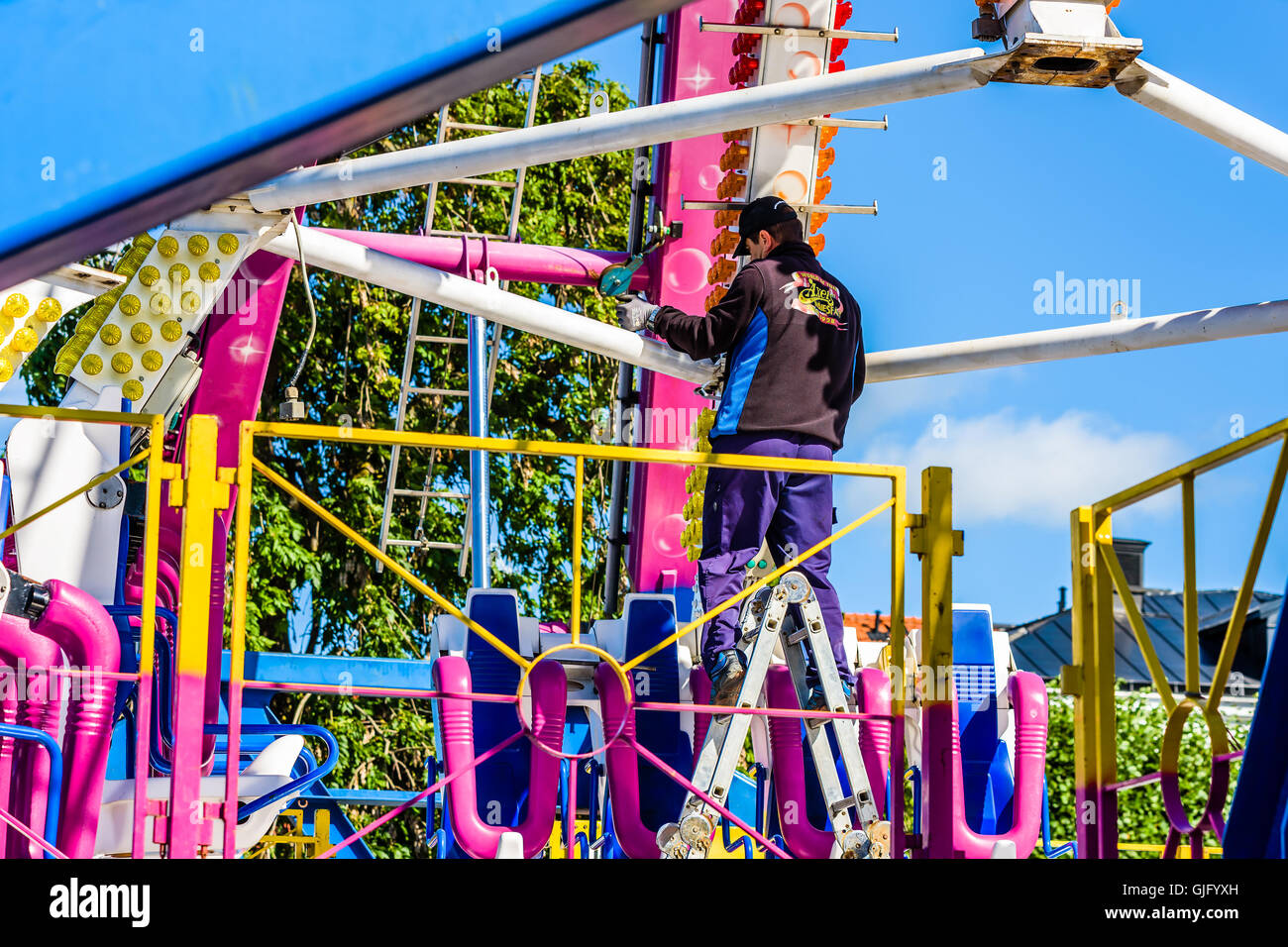 Kalmar, Svezia - Agosto 10, 2016: lavoratore di sesso maschile sulla scala assemblando un divertimento pubblico ride o il carnevale ride per un imminente publ Foto Stock