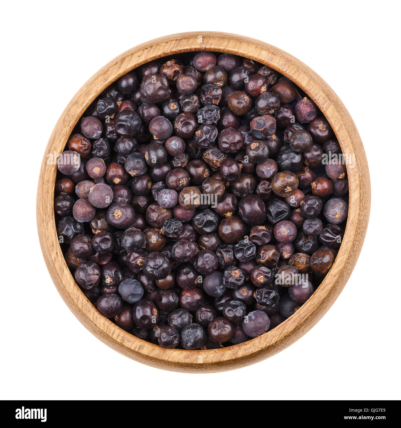 Bacche di ginepro in una ciotola su sfondo bianco. Seme essiccato coni da Juniperus communis, una conifera, vengono utilizzati come spezie. Foto Stock