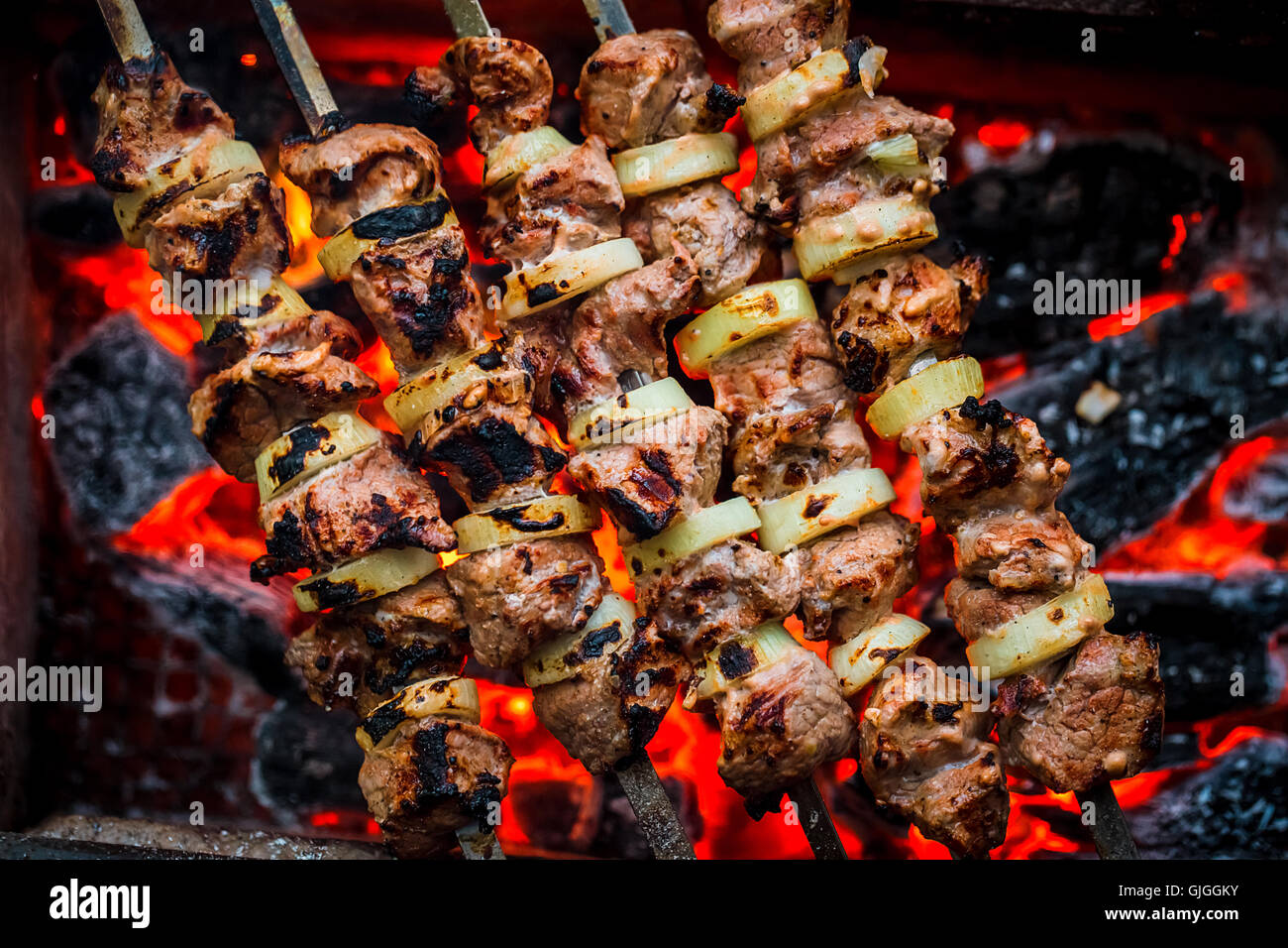 Barbecue spiedini di carne di maiale sul grill caldo close-up. Fiamme di fuoco e i carboni in background Foto Stock