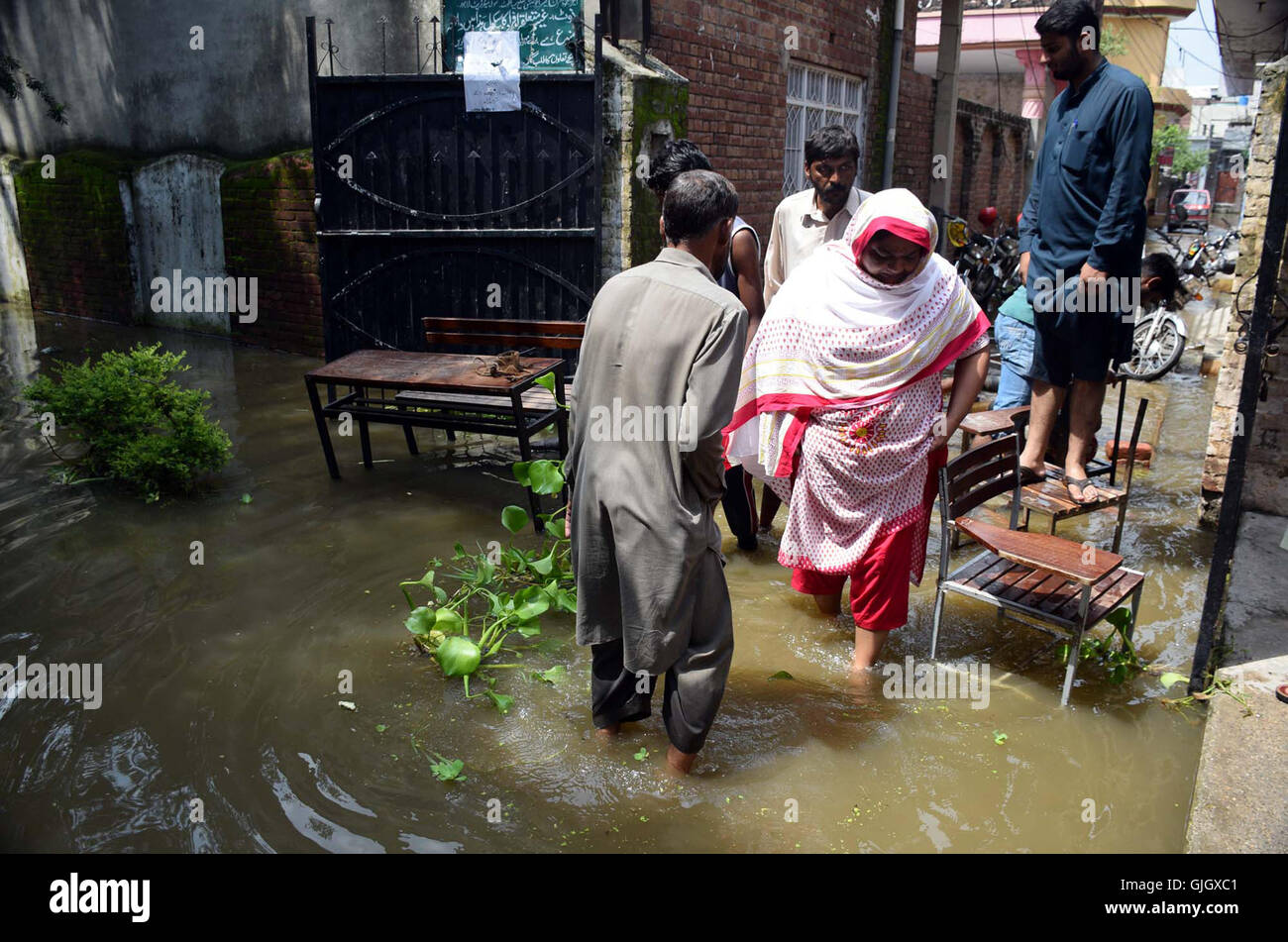 Colpite dalle alluvioni persone passano attraverso il proiettore stagnante come le loro case sono sommerse da acqua di inondazione che ha colpito le aree dopo piogge abbondanti della stagione dei monsoni, in Sialkot Martedì, 16 agosto 2016. Foto Stock