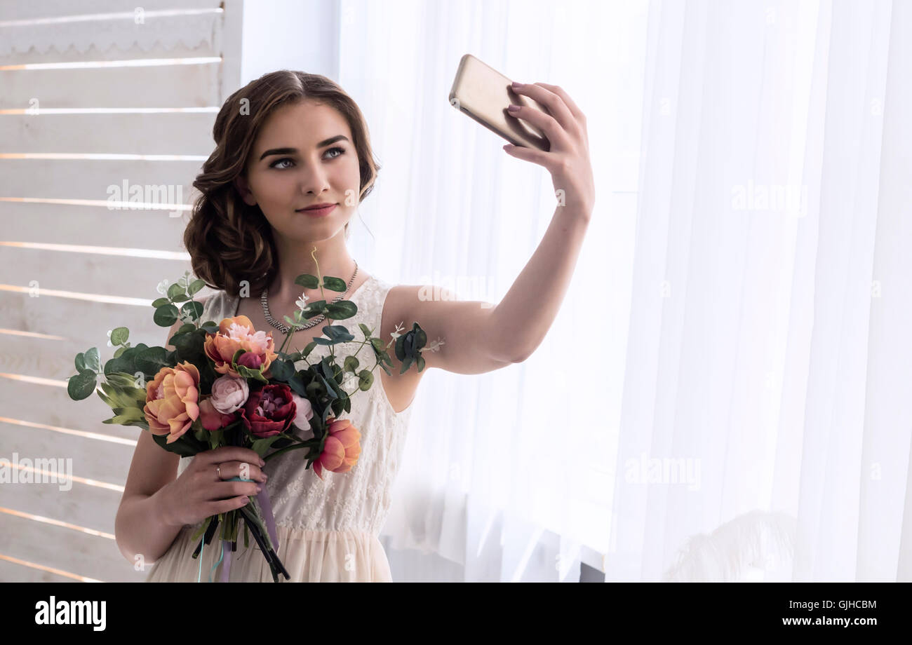 Donna che mantiene bouquet di fiori prendendo un selfie Foto Stock