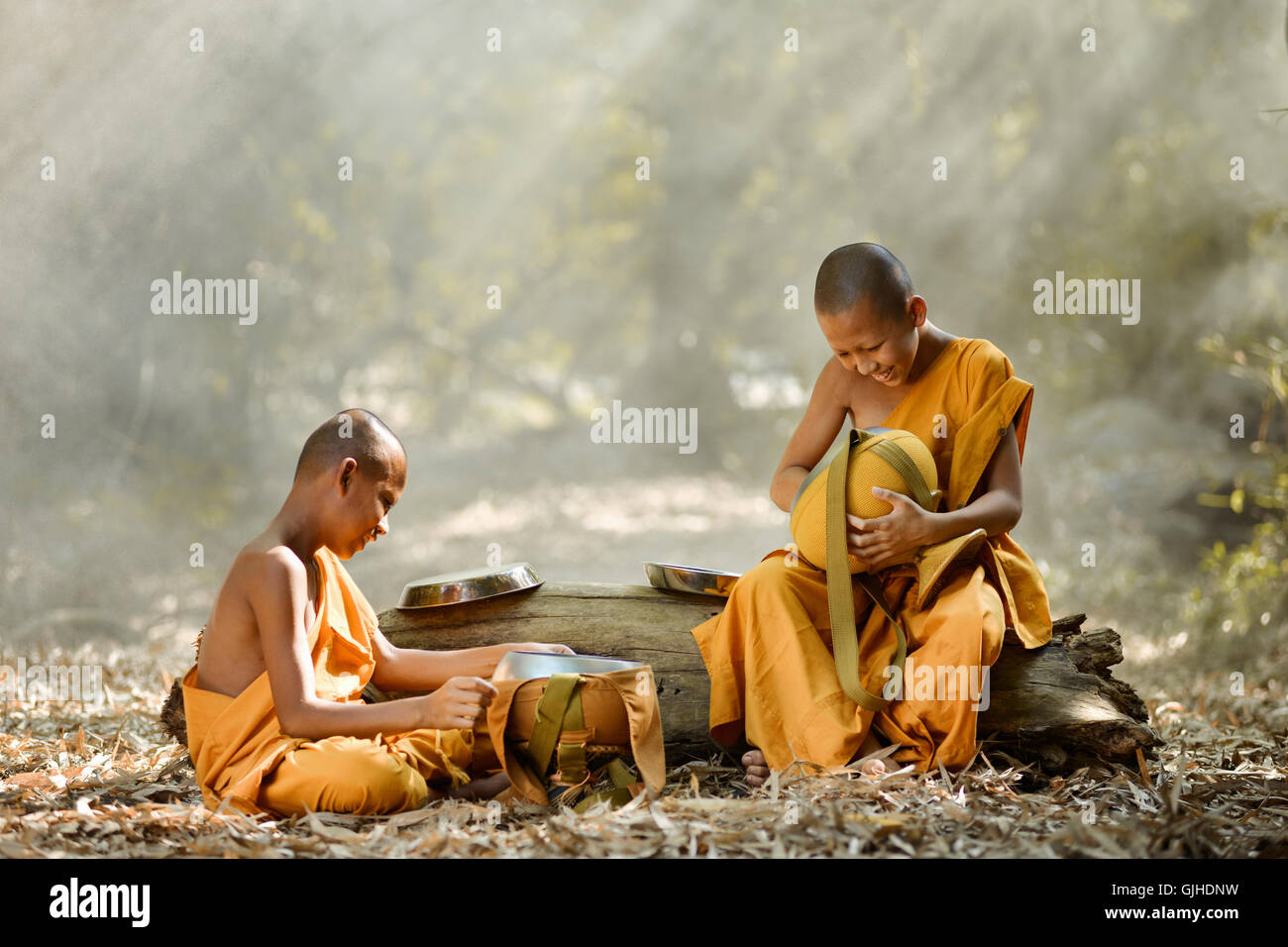 Due novizi Monaci Buddisti seduti in ciotole di cibo di pulizia della foresta, Thailandia Foto Stock