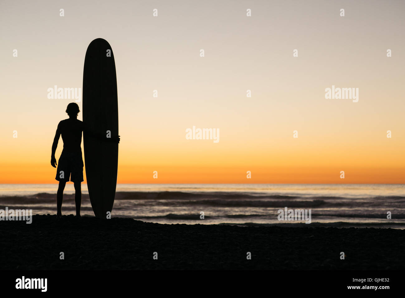 Surfer e il suo bordo godendo di un post navigare bagliore di sera Foto Stock