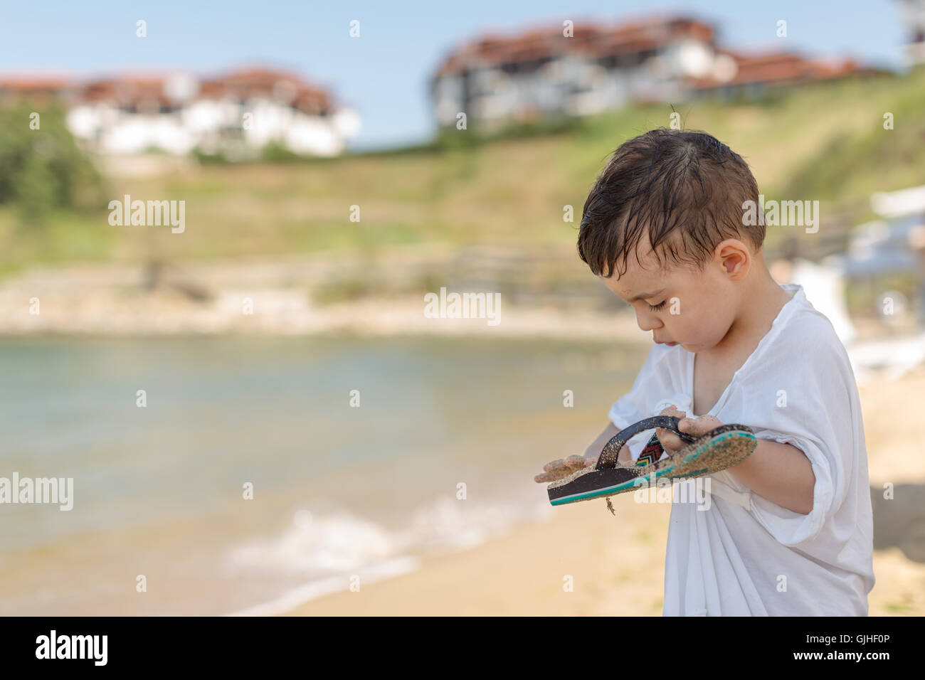 Close-up di un ragazzo in piedi sulla spiaggia di sabbia di spazzolatura off flip-flop, Sozopol Bulgaria Foto Stock