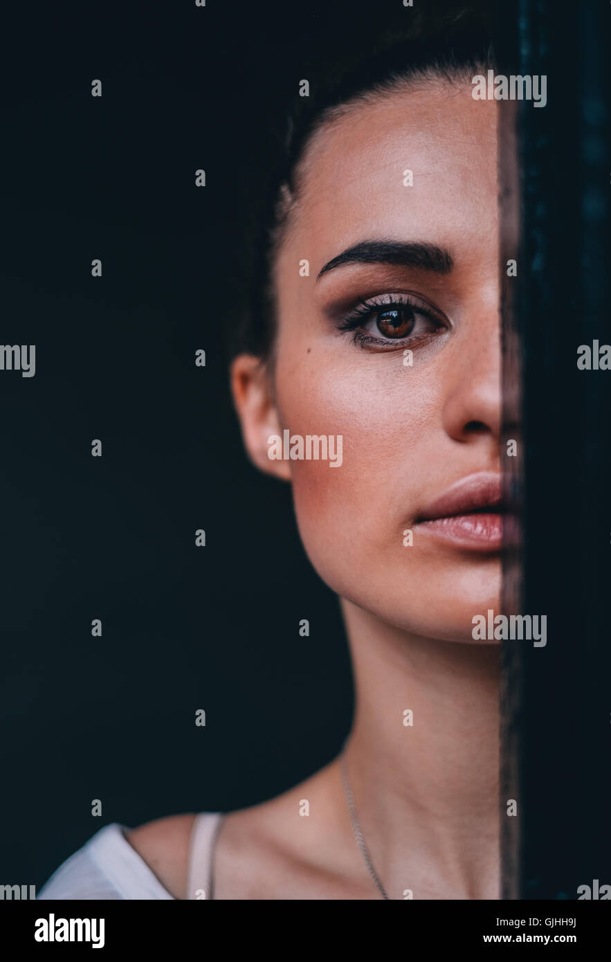 Ritratto di una donna bellissima nasconde metà faccia dietro una cortina Foto Stock