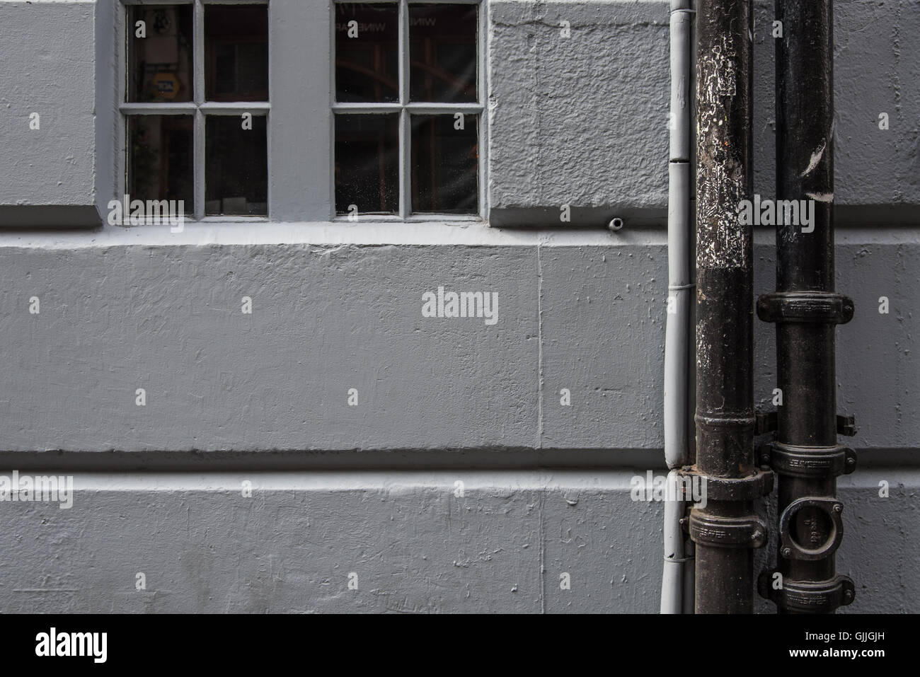 Uno studio di linee urbane. Parete dipinta con tubi pluviali verticali e orizzontali con al centro la finestra del centro delle piazze. Foto Stock