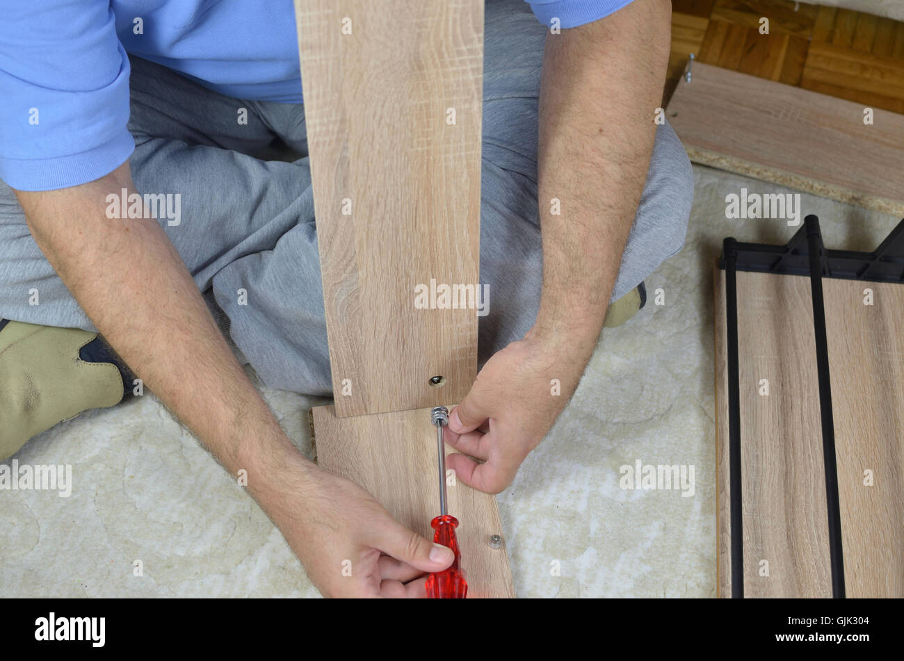 Uomo di assemblare un nuovo scarpa rack parti utilizzando un cacciavite Foto Stock