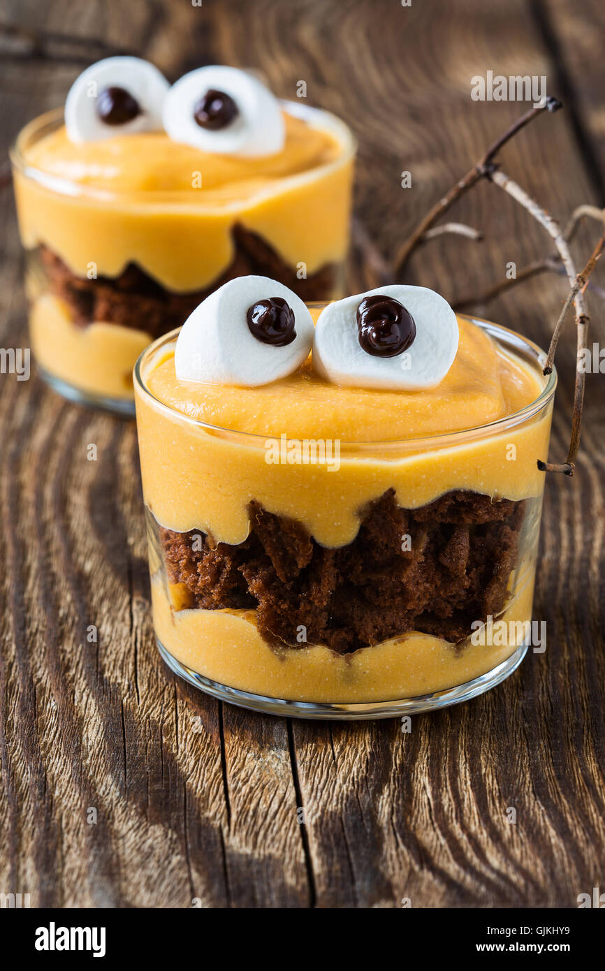 Tratta di Halloween, little monster dessert con biscotti al cioccolato e arancia crema di mascarpone e rabboccato con grandi occhi marshmallow Foto Stock