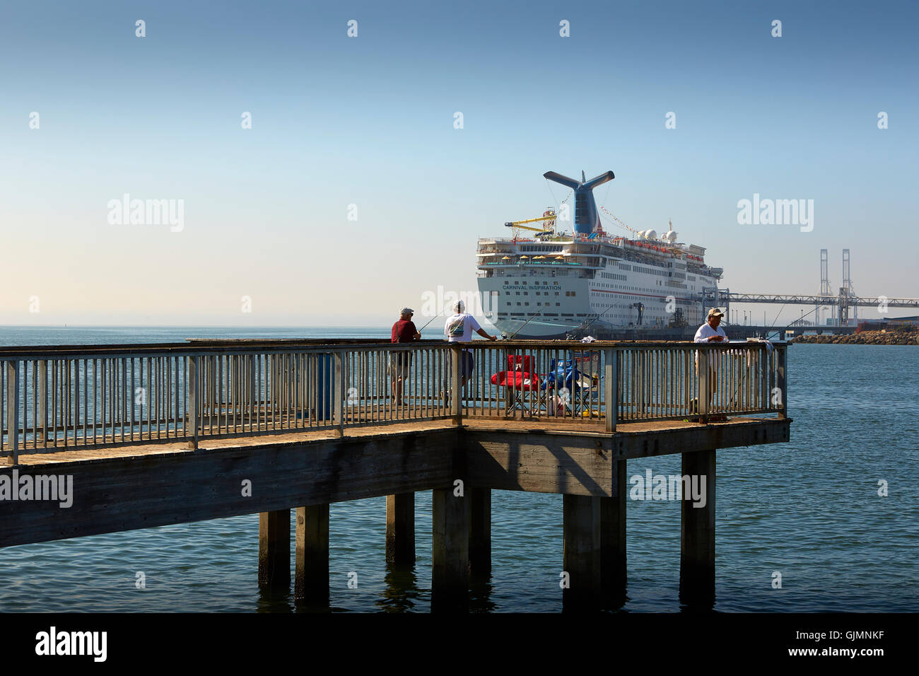 Persone di pesca dal molo che si affaccia il carnevale ispirazione, ormeggiata in Long Beach Harbor, California. Foto Stock