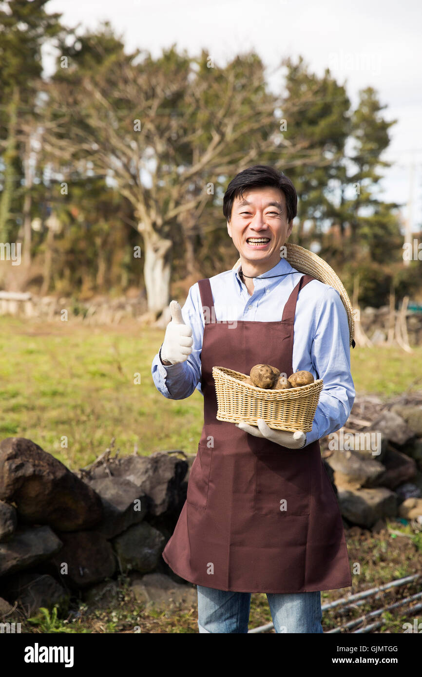 Middleaged Uomo asiatico tenendo le verdure sul campo Foto Stock