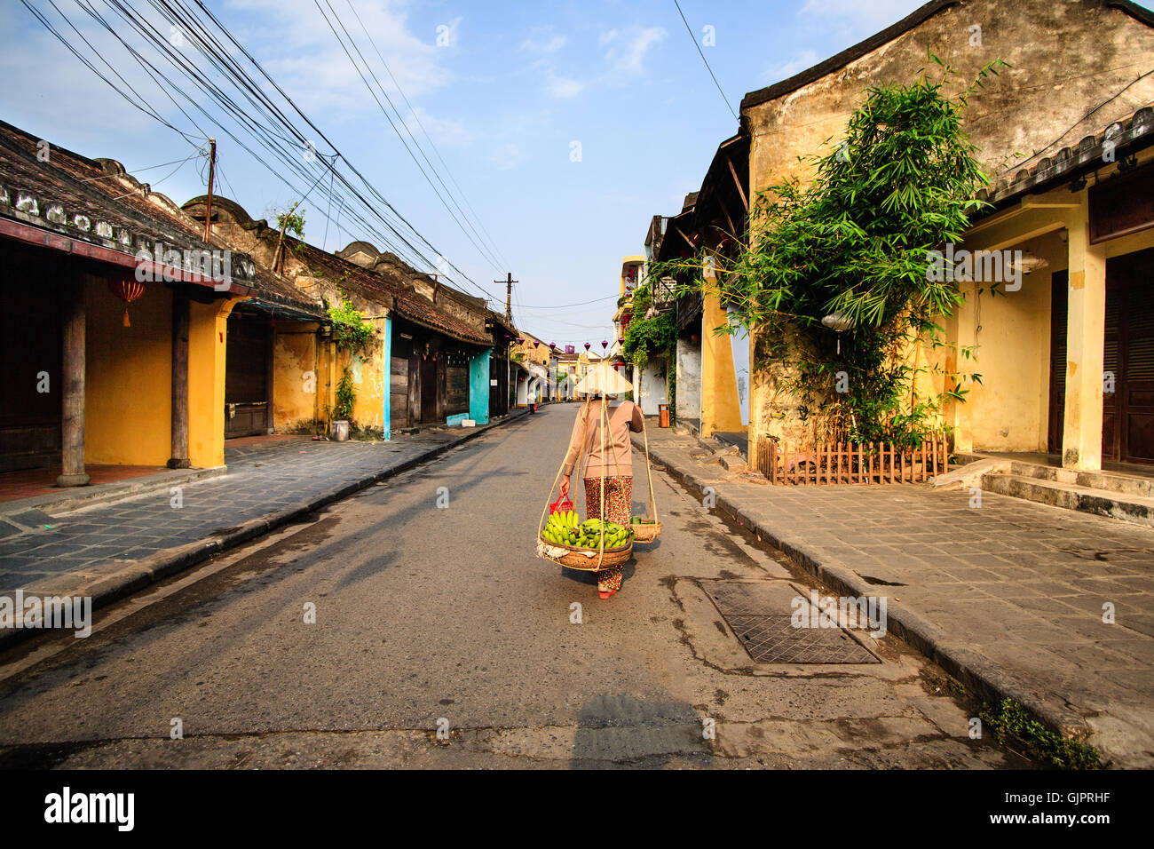 Venditore ambulante alla antica città di Hoi An in inizio di mattina di sole, Quang Nam, Vietnam. Hoi An è riconosciuta come patrimonio mondiale dall'UNESCO. Foto Stock